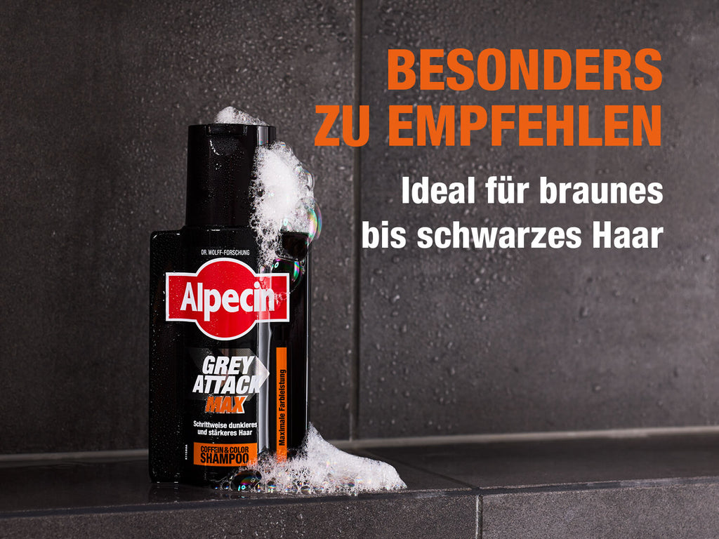 Alpecin Grey Attack MAX Shampoo-Flasche mit Schaum bedeckt, stehend auf einer dunklen, nassen Badezimmerfliese. Die schwarze Flasche trägt das Alpecin-Logo und die Aufschrift ‚Grey Attack MAX – Schrittweise dunkleres und stärkeres Haar – Coffein & Color Shampoo – Maximale Farbleistung‘. Rechts daneben steht in großen orange-weißen Buchstaben: ‚BESONDERS ZU EMPFEHLEN – Ideal für braunes bis schwarzes Haar‘.